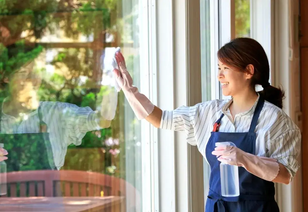 Professional cleaner washing a large window during seasonal spring home cleaning.